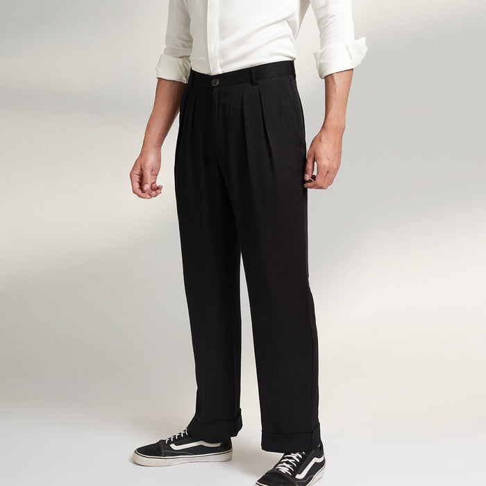 A global medium size model wearing BLACK ORGANIC LOTUS SILK FABRIC TROUSERS. the trouser has a straight comfort fit with turn up bottom and 2 front pleats from house of Parvi.