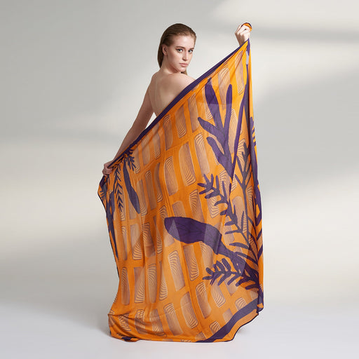 Amahle, a square scarf crafted from an organic Aloe Vera fabric, inspired by the intricate details of antique wall artworks adorned with climbing plant vines. This captivating scarf features a vibrant orange base adorned with elegant purple vine.