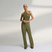 A global small size model wearing a solid olive green jumpsuit, highlighted with hand-stitched smocking on the bodice panel with a drawstring attached to the bodice to tie at the neck. inspired from the vintage window designs.