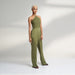 A global small size model wearing a solid olive green jumpsuit, highlighted with hand-stitched smocking on the bodice panel with a drawstring attached to the bodice to tie at the neck. inspired from the vintage window designs.