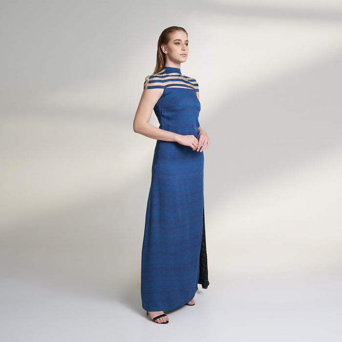 A printed blue long evening dress crafted in organic lotus silk and organza fabric accentuated with a thigh high slit and a short stripe cape attached to the dress.