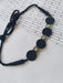 Black choker necklace with round charms in silver and black on white backdrop